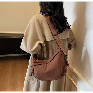 Detailed back view of a brown crescent canvas bag with a wide strap and buckle