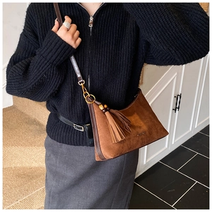 Detail view of brown suede shoulder bag with tassel, wooden beads and leather strap