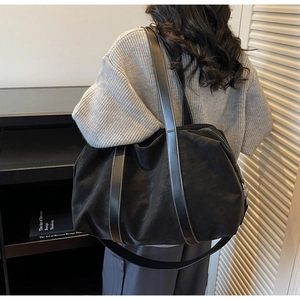 Détail d'un grand sac cabas noir avec de larges anses en cuir et une texture mate chic