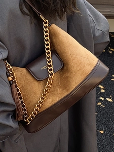 Brown quilted suede hobo shoulder bag with gold chain strap worn by a model in winter