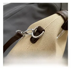 Detail showing the silver metal hook and dark brown leather trim on a canvas bag