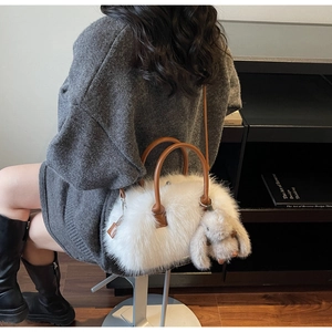Détail du sac cabas en peluche blanche avec anses en cuir marron et pendentif lapin mignon