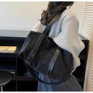 Détail d'un grand cabas noir mat avec coutures blanches contrastées porté par un mannequin