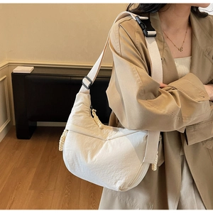 Detail of white nylon crescent bag with adjustable wide strap and woven zip puller detail
