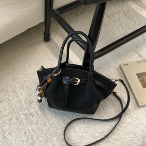 Détail du sac trapèze en daim noir avec pendentif perles et boucle sur tapis de tissage