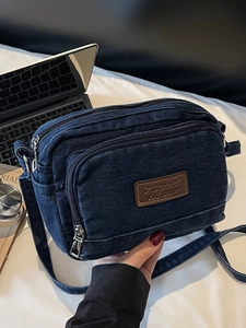 Sac bandoulière en jean bleu foncé avec compartiments zippés et style urbain vintage
