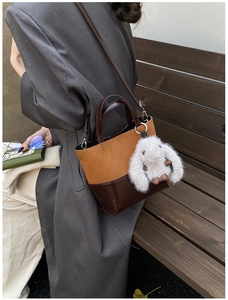 Detail of retro patchwork bucket bag with a cute plush rabbit charm on a grey coat
