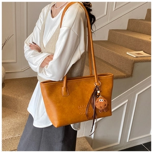Détail du grand sac cabas en similicuir caramel avec lettrage embossé et peluche
