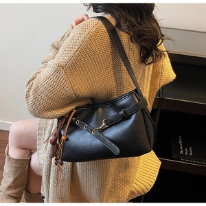 Détail d'un sac à bandoulière vintage en cuir noir avec un long gland élégant et boucle