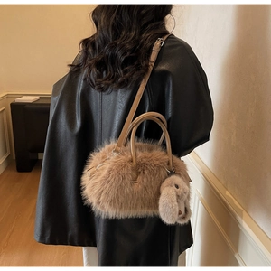 Détail du sac fourre-tout en peluche marron clair avec breloque lapin sur manteau en cuir noir