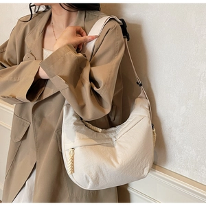 Detail of a cream-colored large capacity canvas hobo bag with adjustable strap and woven zipper