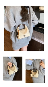 Detail view of beige canvas bucket bag with brown handles and beaded charm accessory