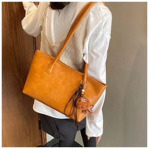 Détail d'un sac cabas vintage marron avec lettrage embossé et bijou de sac peluche