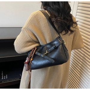 Vue détaillée du sac d'épaule noir en similicuir avec boucles dorées et breloque poupée