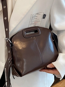Sac bandoulière vintage marron foncé chic avec pompon et sangle sur blazer blanc