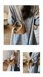 Detail of a brown leather handbag with silver ring handle and bead charm accessory