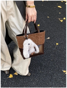 Detail of retro color-block bucket bag with leopard print texture and plush bunny charm