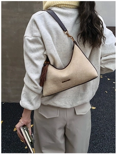 Detail of beige suede crescent bag with dark brown leather straps and moon and sun text