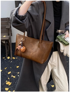 Détail du cabas en cuir grainé caramel avec texte embossé et charmant ours en peluche