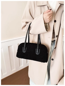 Détail d'un sac à main noir en peluche avec anses en cuir porté par un mannequin en trench-coat