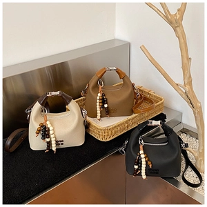 Three fashion handbags in white, brown, and black with beaded charms and metal handles