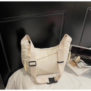 Detail of white quilted nylon crescent bag with wide strap and plastic buckle
