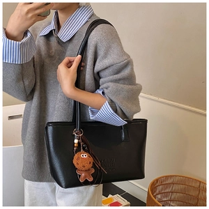 Détail du sac cabas noir texturé avec texte embossé et breloque bonhomme de pain d'épices