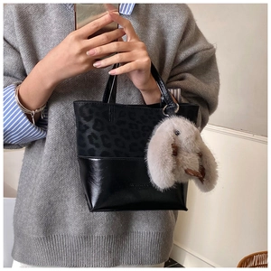 Detail of trendy leopard print bucket bag with a cute plush rabbit charm on the handle