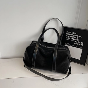 Détail d'un grand sac de voyage noir avec poignées en cuir et fermeture éclair