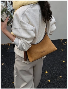 Detail of brown suede crescent bag with fringe accents and metallic zipper hardware