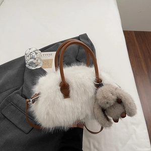 Détail du sac cabas en fausse fourrure blanche avec anses en cuir brun et pendentif lapin