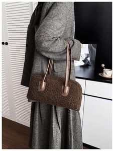 Détail du sac à bandoulière en peluche marron avec des anses en cuir sur un manteau