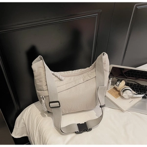 Detailed macro view of the beige nylon crescent bag featuring functional zipper pockets