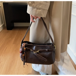 Détail du sac à bandoulière marron foncé vintage avec boucle et charm d'ours