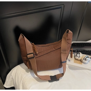 Detail of a brown nylon crescent crossbody bag featuring an adjustable strap and buckle