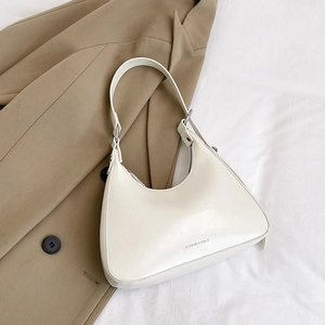 Detailed view of off-white hobo bag with fashion logo on warm beige fabric background