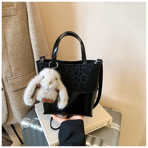 Detail of retro leopard print bucket bag with plush rabbit pendant on lifestyle background