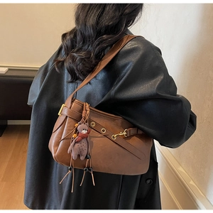 Sac à bandoulière vintage marron avec œillets dorés et charmant pendentif d'ours