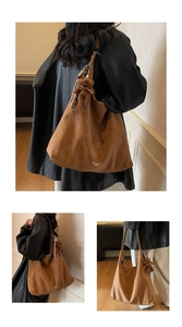 Detailed macro shot of dark brown suede tote bag with teddy bear charm and logo print