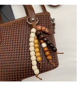 Dettaglio borsa a secchiello intrecciata marrone con ciondolo in perline di legno vintage