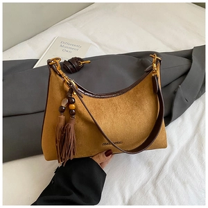 Detail of vintage mustard suede underarm bag with leather trim and decorative tassels