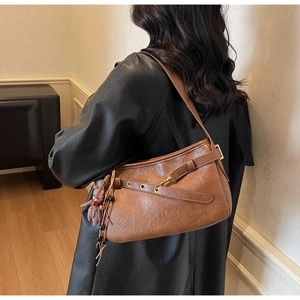 Détail d'un sac porté épaule vintage marron avec sangles en cuir et breloque en peluche