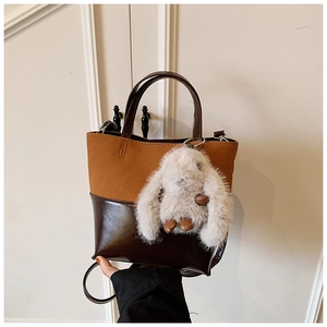 Detail of retro shoulder bucket bag featuring contrast textures and plush rabbit charm