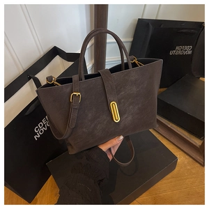 Detailed macro view of the matte leather texture and oval golden buckle on the tote bag