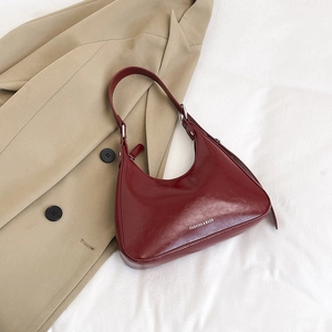 Detail view of burgundy semi-moon shoulder bag in glossy leather with fashion text logo