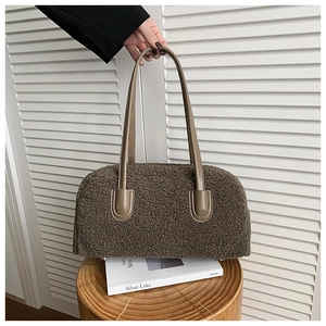 Détail d'un sac cabas en peluche marron avec anse en cuir sur un support en bois minimaliste