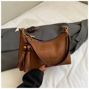 Detailed macro view of brown suede underarm bag with fringe charm and gold hardware