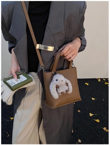 Close-up of brown pebbled leather bucket bag with a cute white plush bunny charm