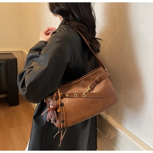 Vue détaillée d'un sac d'épaule vintage en cuir marron avec un joli porte-clés ours