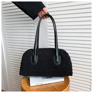 Détail du sac cabas en peluche noire montrant la texture et les anses en cuir lisse